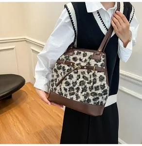 Detailed side view of a large leopard print faux fur tote bag worn by a model