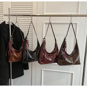 Four retro crescent hobo bags in assorted leather colors hanging on a metal rack