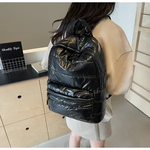 Model wearing a large black quilted puffer backpack with shiny waterproof nylon texture