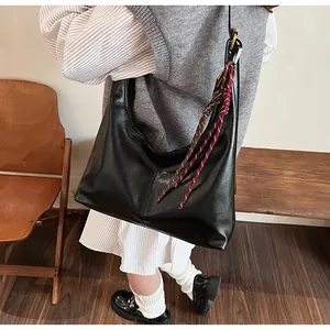 Detail of black crescent hobo bag with woven tassel accent worn by a model