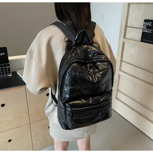 Rear view of model wearing a black quilted puffer backpack with shiny nylon finish