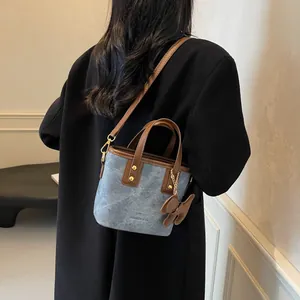 Modische Vintage Eimertasche aus blauem Denim mit braunem Lederbesatz und Bärenanhänger