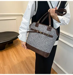 Detail of grey tweed and brown leather tote bag with metal eyelet strap design