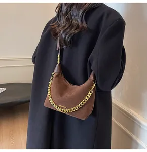 Detailed view of brown suede dumpling bag with decorative chunky gold chain strap