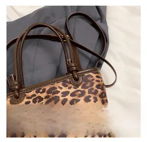 Dettaglio della borsa a secchiello leopardata con manico in pelle marrone e nodi
