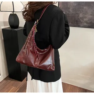 Detail of burgundy glossy leather shoulder bag with decorative braided accents and large capacity