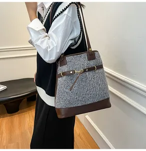 Detail view of large grey tweed tote bag with brown leather trim and gold buckle