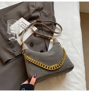 Close-up of dark grey matte moon bag with decorative thick gold chain and leather strap