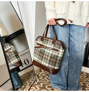 Close-up of retro green plaid tweed tote bag with dark brown leather straps and metal buckle