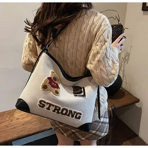 Detail of cream tote bag featuring bear embroidery and stylish black leather corner guards