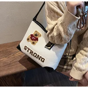 Detail of canvas tote bag with plush bear embroidery and vintage varsity style patches