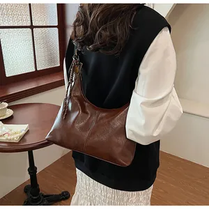 Brown retro high-gloss leather shoulder bag with decorative tassel and classic crescent design
