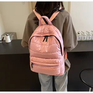 Detail of pink quilted puffer backpack with soft padded texture and top handle shown on model