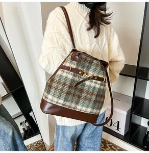 Detail of vintage green plaid tweed backpack with dark brown leather straps and metal buckles