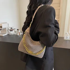 Grey suede hobo bag with bold gold chain detail and adjustable strap shown from behind