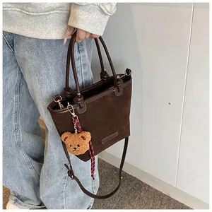 Borsa a secchiello in pelle scamosciata marrone scuro con manico e ciondolo a orsetto