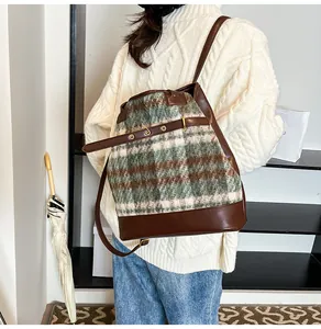 Macro detail of the vintage plaid wool fabric and dark brown leather strap of the backpack