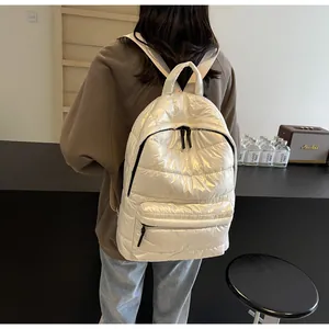 Detailed view of glossy white quilted backpack featuring pearl sheen and metal zipper