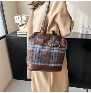 Detail of vintage plaid tote bag with brown leather straps and gold buckle accents