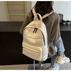 Detail of white quilted puffer backpack featuring shiny texture and adjustable straps