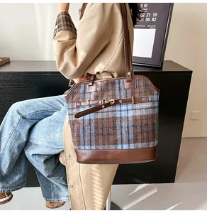 Detail of vintage plaid tote bag with brown leather trim and stylish belt buckle accents