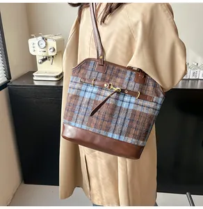 Detail of vintage plaid tote bag featuring brown leather trim and golden metal buckles