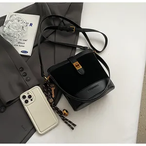 Détail du sac seau en cuir noir avec fermoir tournant doré et texture en daim patchwork