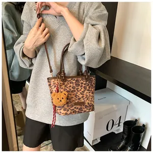 Dettaglio della borsa a secchiello leopardata con manici marroni e ciondolo a orsetto
