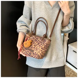 Borsa a secchiello leopardata indossata con ciondolo a forma di orso e tracolla regolabile