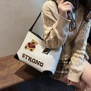 Retro cream canvas tote bag with embroidered bear and leather trim worn by model