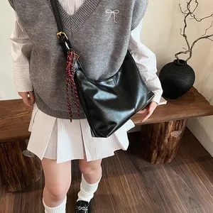 Black hobo shoulder bag in glossy leather with woven pendant shown on model