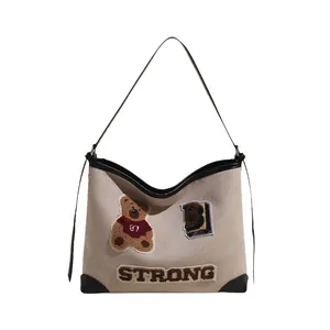 Classic cream canvas tote bag with retro teddy bear embroidery and black trim accents