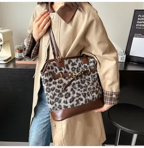 Detail of leopard print faux fur tote bag featuring brown leather trim and golden buckle