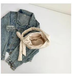 Détail rapproché du sac matelassé beige avec une poche intérieure et une fermeture