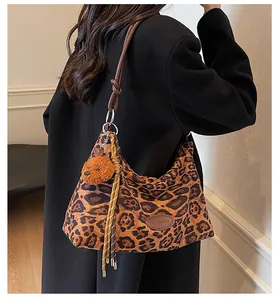 Detailed view of leopard print tote bag with plush bear charm and striped tassel detail