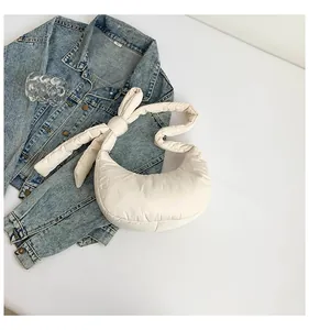 Gros plan du sac matelassé en demi-lune blanc crème avec une bandoulière à nœud unique