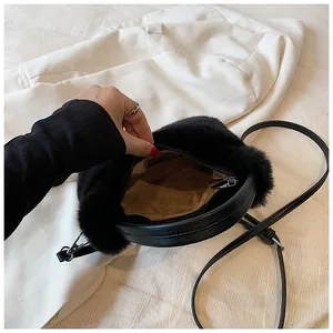 Detail of black faux fur handbag with circular handle and zipper showing inner lining