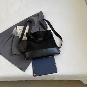 Macro shot of large black suede tote bag showing spacious interior with tablet and zipper