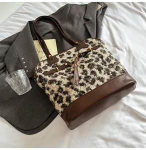 Detail of leopard print plush tote bag with brown faux leather bottom and gold hardware