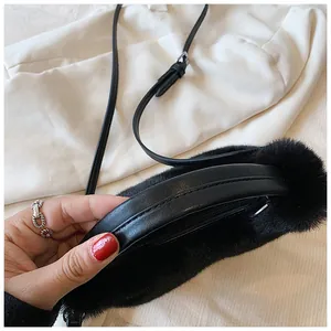 Detail of black faux fur handbag featuring leather strap and silver metal hardware accents