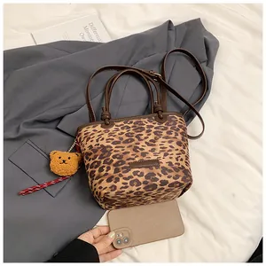 Dettaglio della borsa a secchiello leopardata con cinturini marroni e ciondolo a forma di orso
