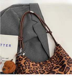Detail of leopard print tote bag with brown knotted rope strap and plush bear charm