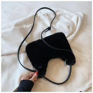Detail of a black faux fur crescent bag placed on a white blazer, showing soft plush texture
