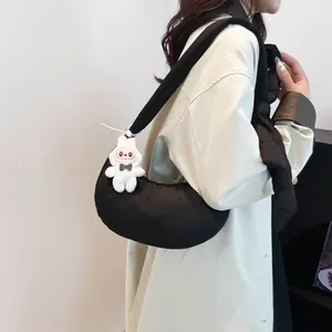 Sac croissant matelassé noir avec pendentif lapin en peluche blanc porté par un modèle