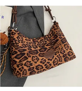 Detail of leopard print plush tote bag with brown leather strap and cute bear charm
