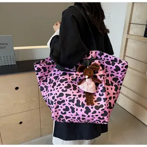Dettaglio della borsa tote rosa con stampa mucca, ciondolo a topo e tracolla larga in nylon