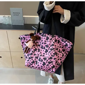 Dettaglio della borsa tote rosa con stampa mucca, ciondolo peluche e manici neri larghi