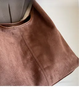 Close-up of coffee brown suede texture and leather edge detailing on a minimalist tote bag