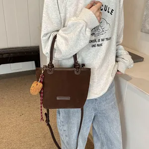 Borsa a secchiello in camoscio marrone con ciondolo decorativo indossata da una modella