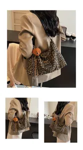 Detail view of large leopard print tote bag with plush bear charm and leather strap